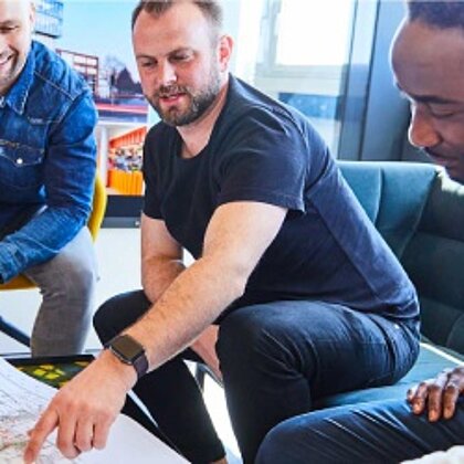 Drei Personen schauen sich einen Architekturplan an.