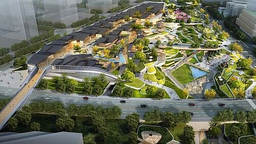 Blick von oben auf ein architektonisch auffälliges Einkaufszentrum, umgeben von viel Grün.