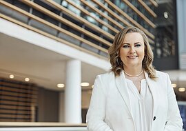 Joanna Fisher befindet sich in der Hauptzentrale der ECE und lächelt freundlich in die Kamera.