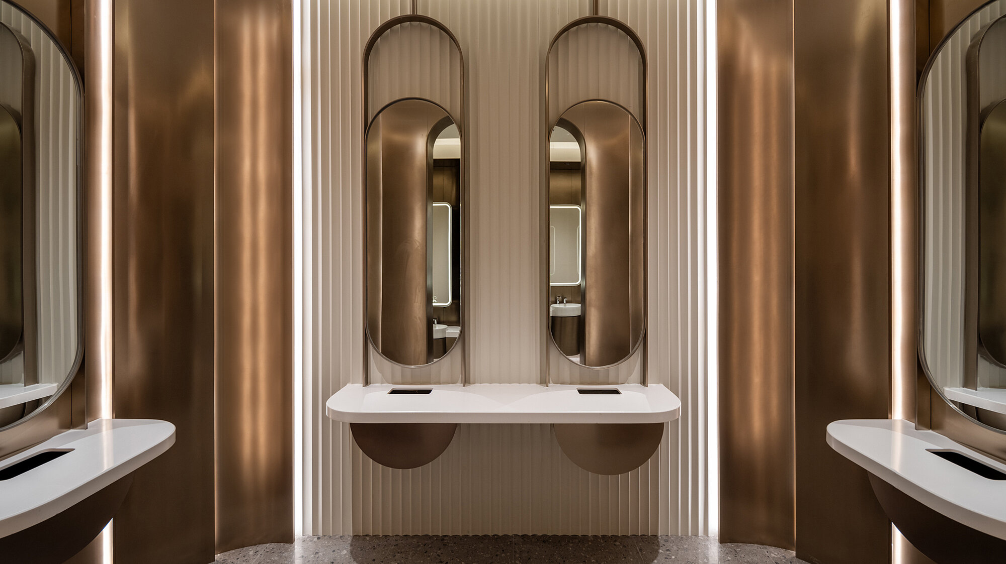 Interior view of a room with mirrors and washbasin, the wall of which is designed in brown and white.