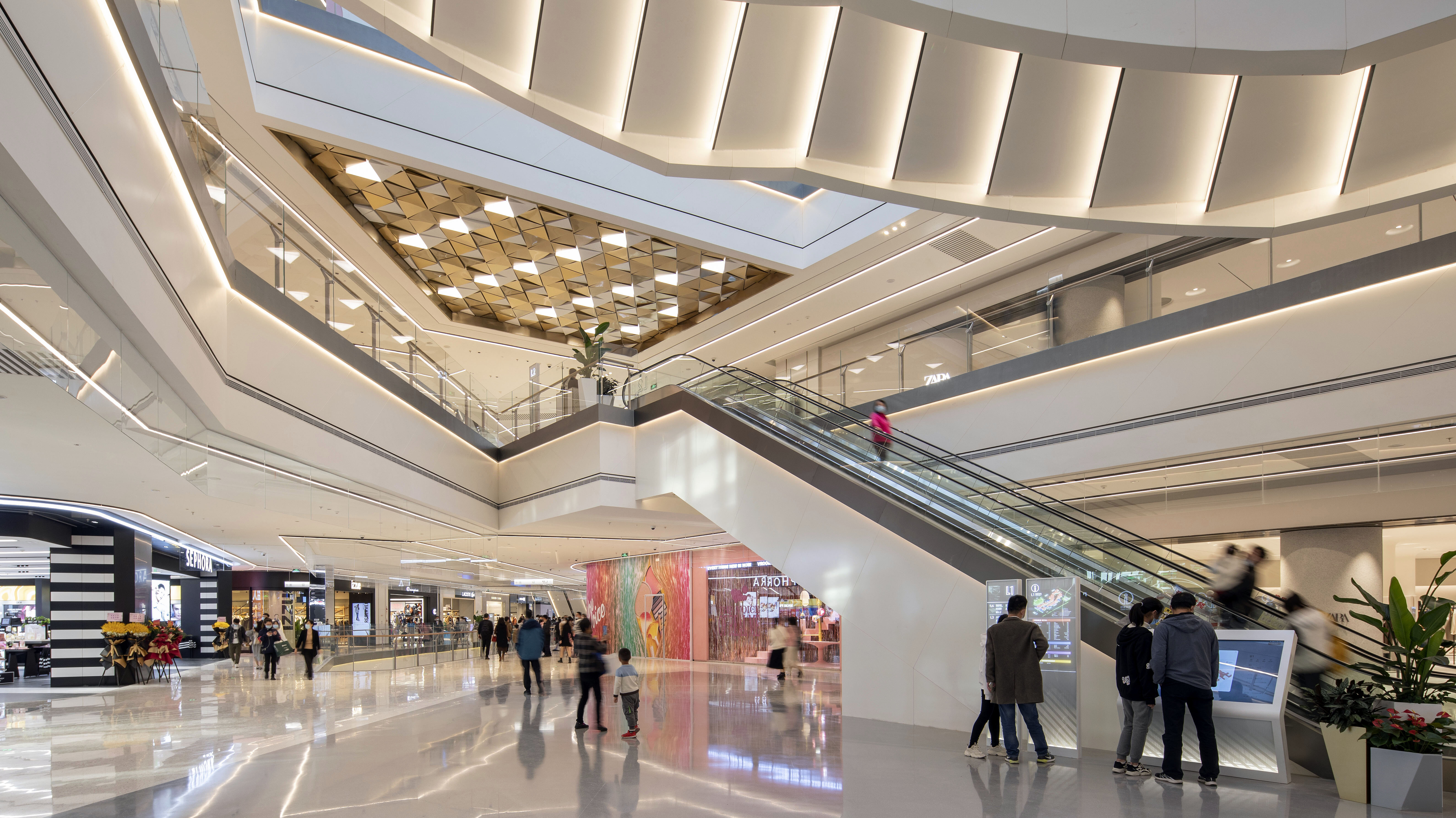 Ein helles, zeitgemäß gestaltetes Einkaufszentrum mit zahlreichen Besucherinnen und Besuchern.