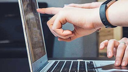 Ein Finger zeigt auf den Bildschirm eines Laptops 