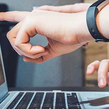 A finger points to the screen of a laptop