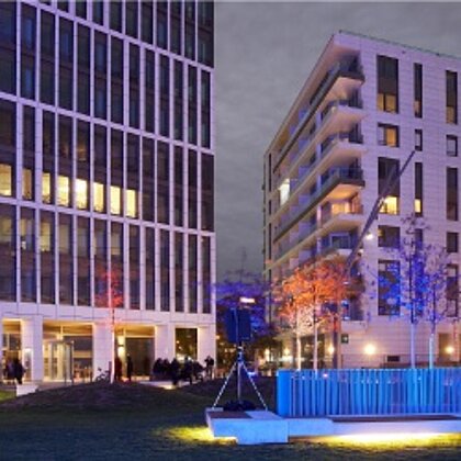 Blick auf ein modernes Hochhausgebäude, mit bunt beleuchteten Innenhof.