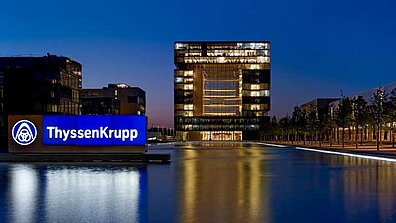 View of an illuminated ThyssenKrupp office building at night.