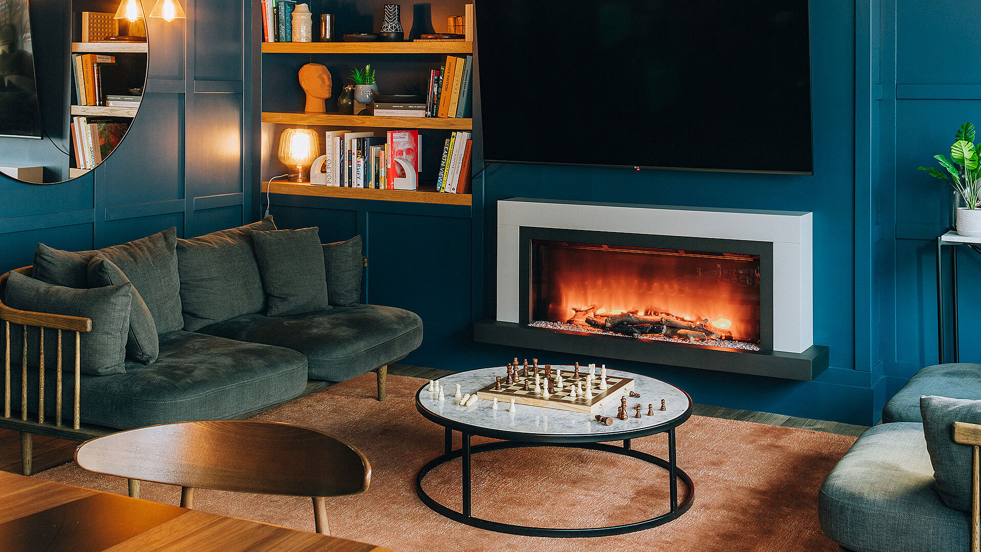 Blick auf ein Wohnzimmer mit blauen Wänden, einem Kamin und diversen Dekorationen.