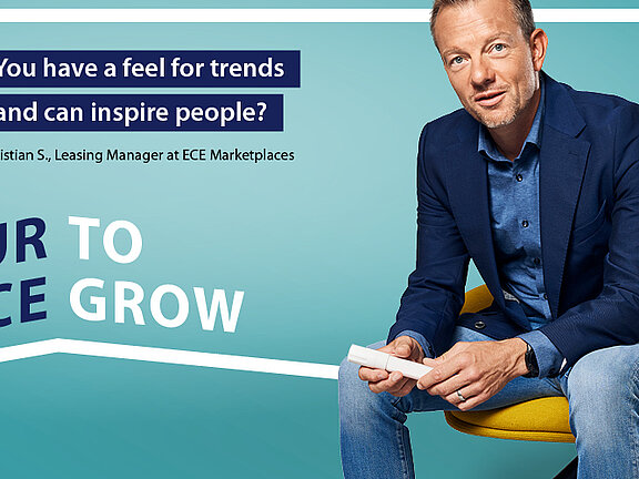 A man in front of a turquoise background, in the background a frame bearing the words "Creating space. Inspiring people. We give you space to inspire people. Find your place with us. Your space to grow.".