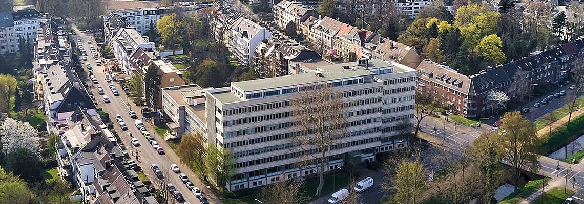 Ein ehemaliges Bürogebäude in Düsseldorf, umgeben von Wohnanlagen und viel Grün.