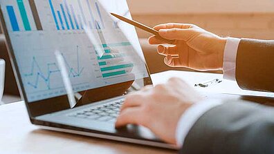 Two hands working on a laptop. Diagrams are displayed on the screen.