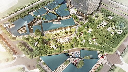 Vogelperspektive auf ein modernes Shopping-Areal mit markanten Dächern inmitten grüner Umgebung.