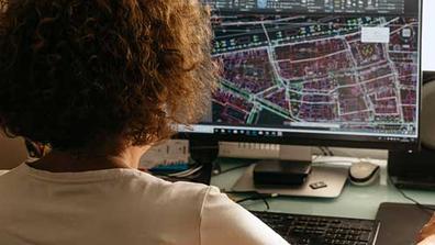 Eine Person arbeitet an einem Bauplan auf einem PC