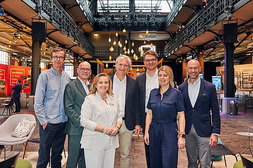 Alexander Otto, Joanna Fisher und weitere Personen befinden sich in einer Veranstaltungs-Location und lächeln freundlich in die Kamera.