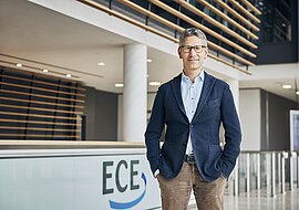 Robert Heinemann befindet sich in der Hauptzentrale der ECE und lächelt freundlich in die Kamera.