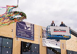 Auf dem Bild ist ein Richtkranz zu sehen, daneben ein Baukran.