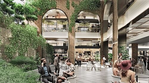 Innenansicht eines Einkaufszentrums mit entspannten Besuchern an Sitzbereichen und einer üppigen Bepflanzung, die für eine grüne Atmosphäre sorgt.