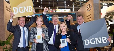 Several people in formal dress pose with two certificates and hold signs that read DGNB (German Sustainable Building Council).
