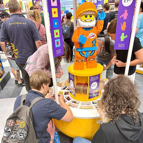 Zwei Personen befinden sich über einer Auslage mit LEGO-Bausteinen.