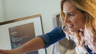 A blonde woman shows something on a screen to another person.