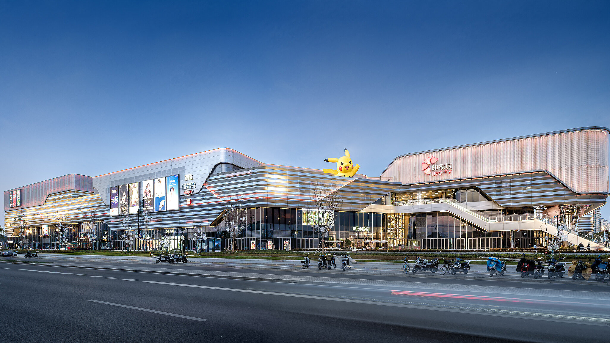 View of a large street in the foreground and a large shopping centre building behind it.