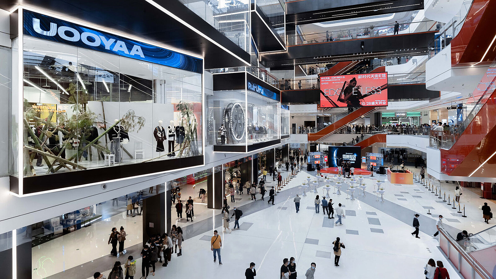 View of a modern mall with unusually designed display windows and lots of people.