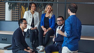 Es sind fünf Personen abgebildet, die sich unterhalten.