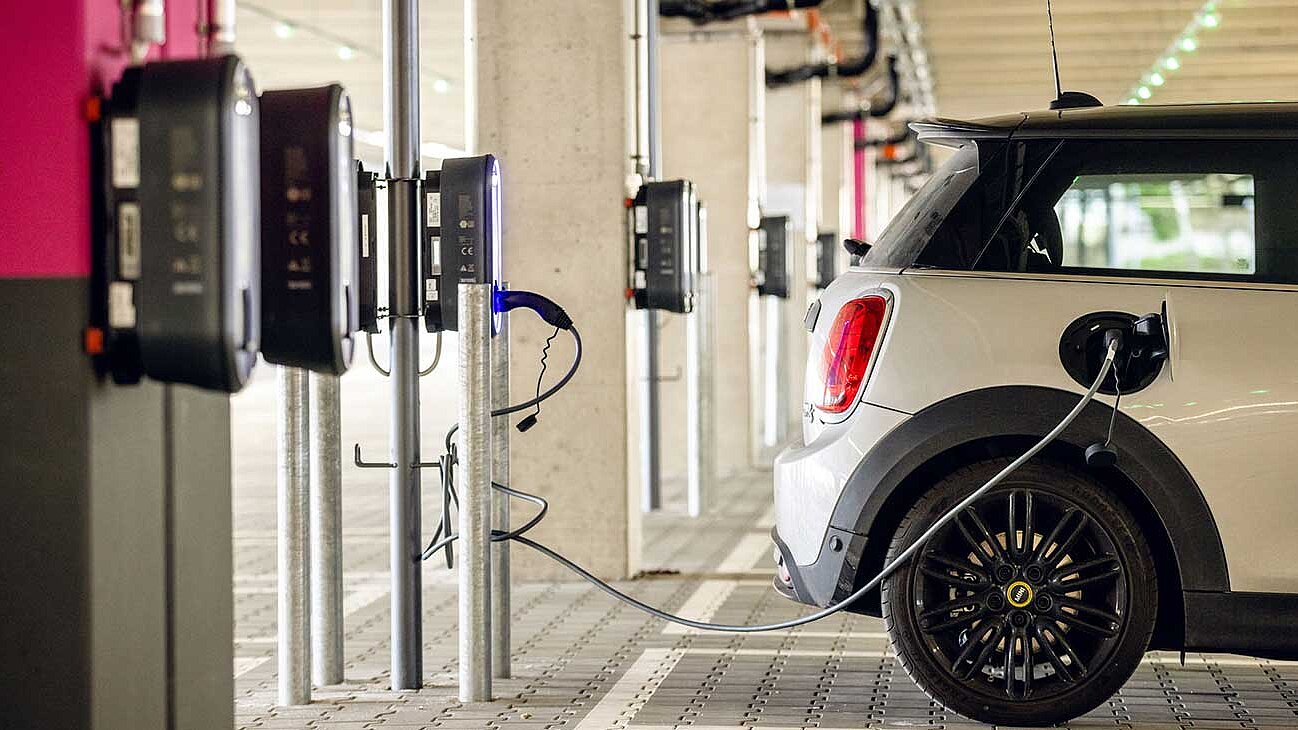 An electric car is parked in a parking space and connected to a charging station
