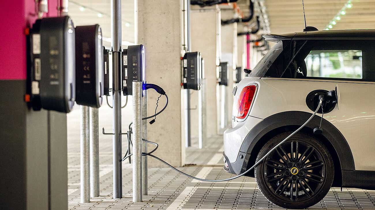 An electric car is parked in a parking space and connected to a charging station
