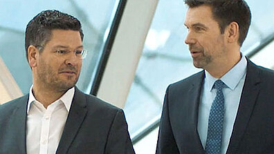 Zwei Männer in Geschäftskleidung stehen nebeneinander