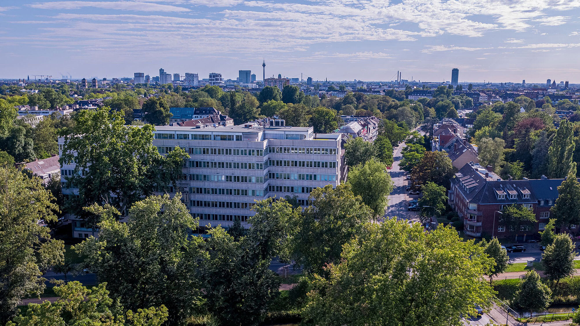 Aerial view of an area in Düsseldorf with some trees in the foreground and large residential buildings standing out.