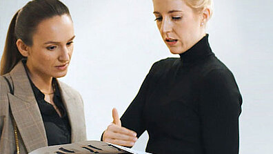 Zwei Frauen in formeller Kleidung tauschen sich aus