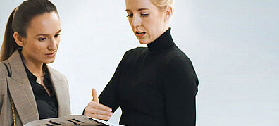 Two women in formal dress exchange ideas