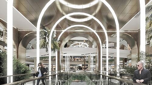 Ein elegantes, modern gestaltetes Einkaufszentrum mit auffälligen Lichtbögen, üppiger Bepflanzung und einigen Menschen.