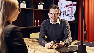 Auf dem Bild ist ein Mann zu sehen, im Gespräch mit einer Frau.