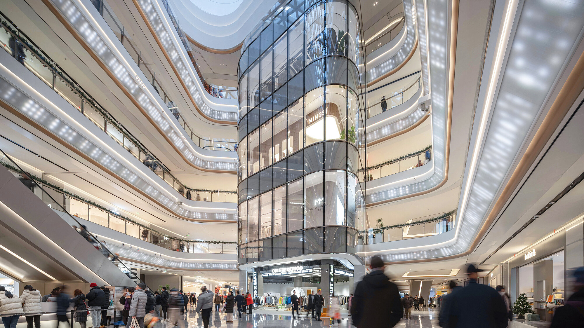 Ein helles, zeitgemäß gestaltetes Einkaufszentrum mit zahlreichen Besucherinnen und Besuchern.