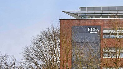 Elevation of a building whose façade is partially covered with a textiles air filter on which an ECE logo can be seen.