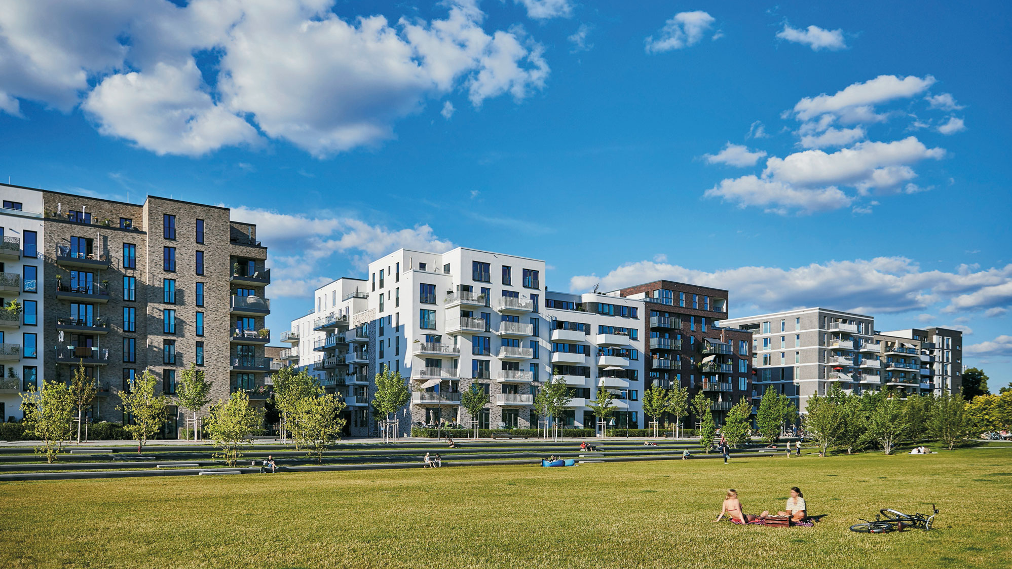 View of a green meadow and a row of tall buildings in the background.