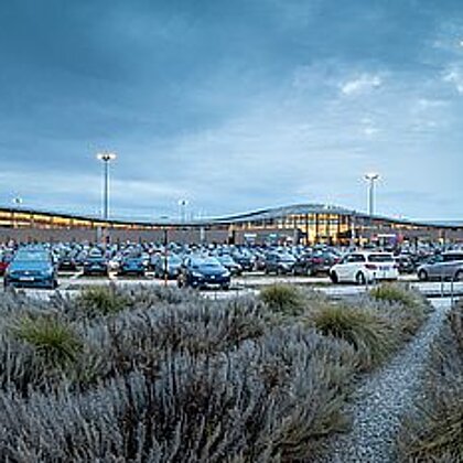 A parking space with many cars in front of the G3 Gerasdorf shopping center