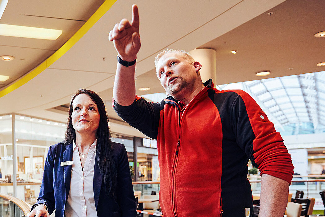 Es sind eine Frau und ein Mann im Center abgebildet, die über etwas diskutieren.