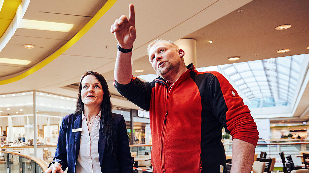 Es sind eine Frau und ein Mann im Center abgebildet, die über etwas diskutieren.