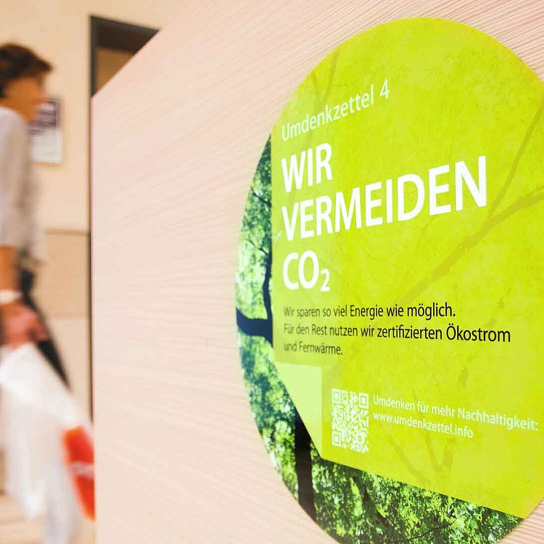 Eine grüne Plakette mit der Aufschrift &quot;Wir vermeiden CO2&quot;, die in einem Shopping-Center angebracht ist