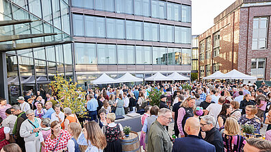 Many people are gathered on the decorated ECE campus, standing in front of stalls and at tables
