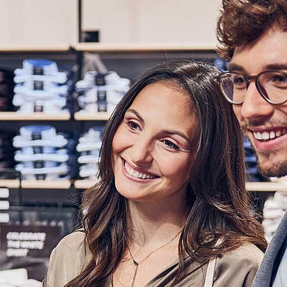 Die Inhaberin von "Fay's Dressroom" hält ein Kleidungsstück an eine Kundin