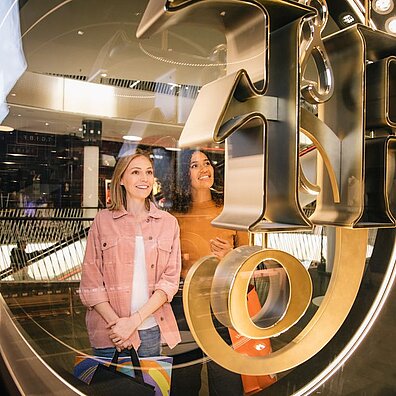 Two shopping center visitors look at something in a display window