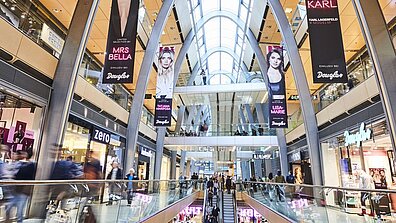 Bazı Werbeplakate hängen von der Decke eines gut besuchten Shopping-Centers