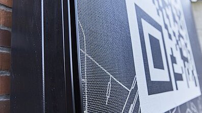 Ein grauer Textilfilter ist an einer Gebäudefassade angebracht