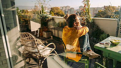 A woman with sits relaxed on a balcony